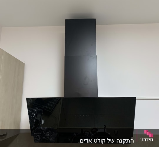 קולט אדים שחור מותקן על קיר מטבח